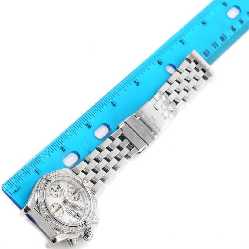 The image shows a top-down view of a Breitling Windrider A13357 Stainless Steel Mother of Pearl Dial A13357 Stainless Steel Mother of Pearl Dial watch with a metal bracelet against a blue ruler for size reference.