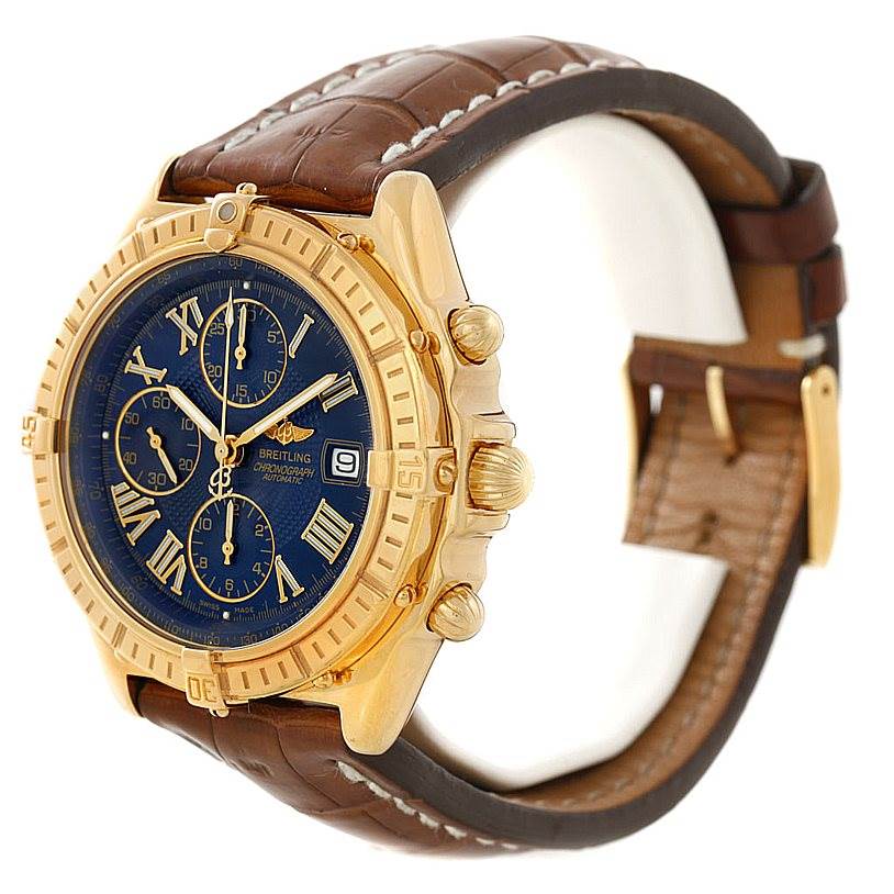This Breitling Windrider K13055 Men
s Yellow Gold Blue Dial K13055 Men
s Yellow Gold Blue Dial watch is shown at an angle displaying the dial, gold case, crown, pushers, and brown leather strap.