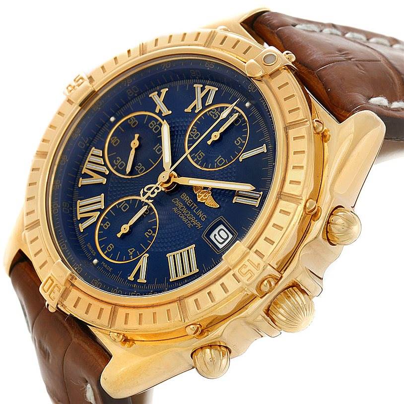 The Breitling Windrider K13055 Men
s Yellow Gold Blue Dial K13055 Men
s Yellow Gold Blue Dial watch is shown at a tilted angle, showcasing the blue dial, gold bezel, chronograph subdials, and brown strap.