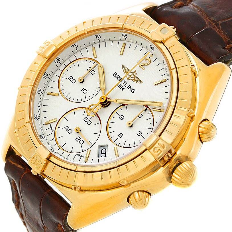 This is a Breitling Windrider K55046 Men's Yellow Gold White Dial K55046 Men's Yellow Gold White Dial watch shown from an angled close-up, displaying the face, gold case, crown, and part of the leather strap.