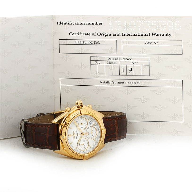 The image shows a Breitling Windrider K55046 Men's Yellow Gold White Dial K55046 Men's Yellow Gold White Dial watch angled to display its face and band, alongside its certificate of origin and warranty.
