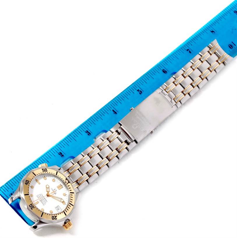The Omega Seamaster Men's Steel and Gold (two tone) White Dial Men's Steel and Gold (two tone) White Dial watch is shown from the top, with a focus on its face, bezel, and metal bracelet next to a ruler for scale.