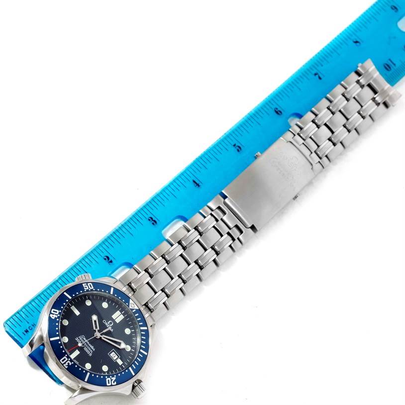 The Omega Seamaster 2541.80.00 Men
s Stainless Steel Blue Dial 2541.80.00 Men
s Stainless Steel Blue Dial watch is shown from a top-down angle with its full bracelet extended alongside a blue ruler for scale.