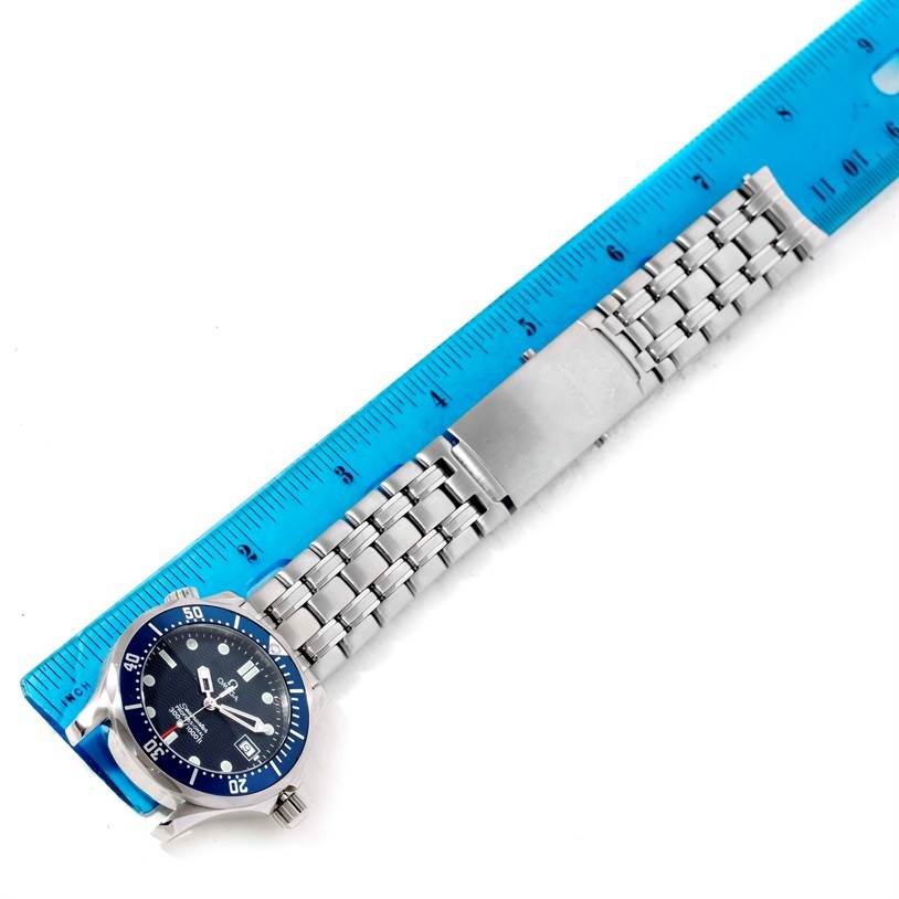 The Omega Seamaster 2561.80.00 Men
s Stainless Steel Blue Dial 2561.80.00 Men
s Stainless Steel Blue Dial watch is displayed laying flat, showing its face, bezel, and metal bracelet beside a blue ruler for scale.