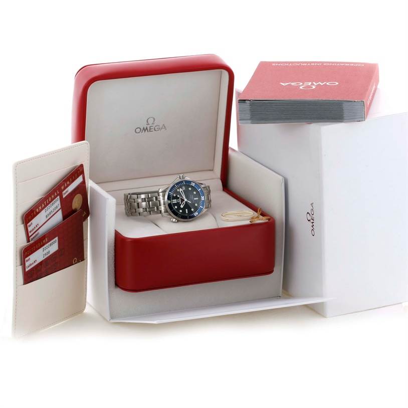 The image shows the Omega Seamaster 2222.80.00 Men
s Stainless Steel Blue Dial 2222.80.00 Men
s Stainless Steel Blue Dial watch inside its red and white box, with accompanying cards and booklet outside the box.