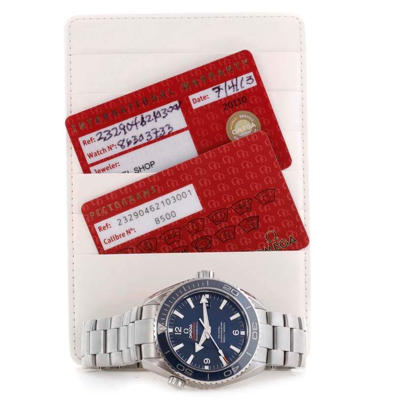 The image shows an Omega Seamaster 232.90.46.21.03.001 Men
s Titanium Blue Dial 232.90.46.21.03.001 Men
s Titanium Blue Dial watch placed with its warranty cards on a flat surface from a top-down angle.
