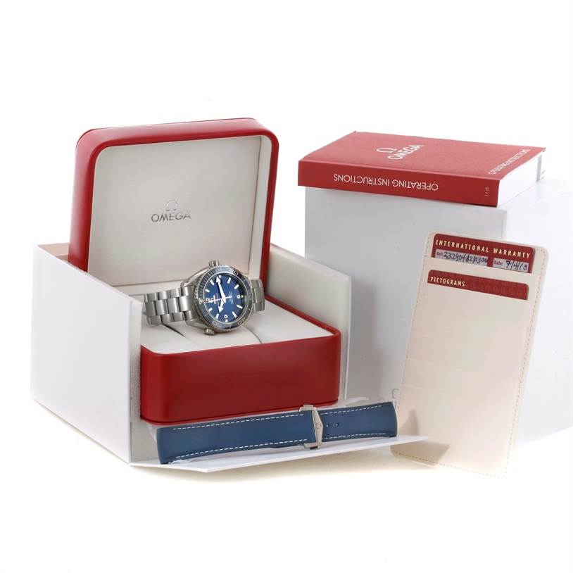 The image shows an Omega Seamaster 232.90.46.21.03.001 Men
s Titanium Blue Dial 232.90.46.21.03.001 Men
s Titanium Blue Dial watch in its open box with a metal bracelet, along with the operating instructions, warranty card, and an additional blue strap.