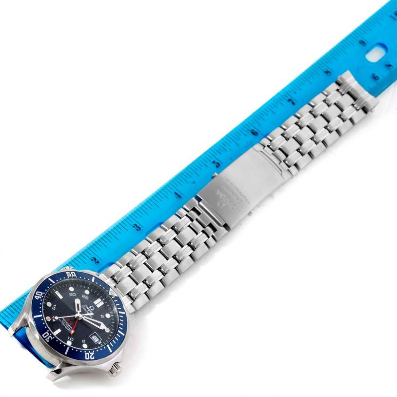 The Omega Seamaster 2535.80.00 Men
s Stainless Steel Blue Dial 2535.80.00 Men
s Stainless Steel Blue Dial watch is shown from a top-down angle, displaying the face, bezel, and full metal bracelet next to a blue ruler.