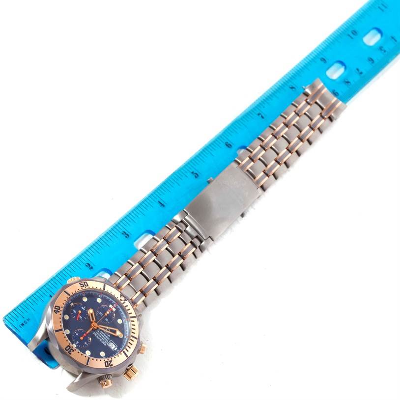 The Omega Seamaster 2296.80.00 Men's Titanium Blue Dial 2296.80.00 Men's Titanium Blue Dial watch is shown horizontally with its face, bezel, and stainless steel bracelet visible next to a blue ruler.