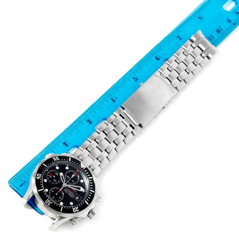 The image shows the front of an Omega Seamaster 213.30.42.40.01.001 Men
s Stainless Steel Black Dial 213.30.42.40.01.001 Men
s Stainless Steel Black Dial watch, with its stainless steel bracelet fully extended next to a blue ruler for measuring.
