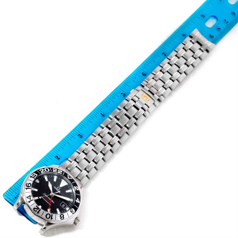 The image shows an Omega Seamaster 2534.50.00 Men
s Stainless Steel Black Dial 2534.50.00 Men
s Stainless Steel Black Dial watch positioned next to a blue ruler, displaying its full length and metal bracelet.