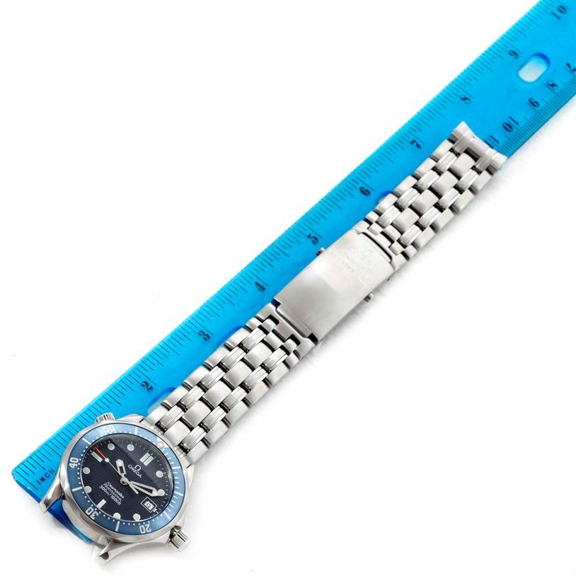 The image shows a top-down view of an Omega Seamaster 2561.80.00 Men
s Stainless Steel Blue Dial 2561.80.00 Men
s Stainless Steel Blue Dial watch, showcasing its face, bezel, and metal bracelet alongside a blue ruler for scale.