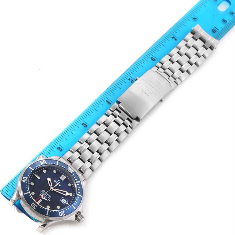 The image shows an Omega Seamaster 2537.80.00 Men
s Stainless Steel Blue Dial 2537.80.00 Men
s Stainless Steel Blue Dial watch with a metal bracelet and clasp, laid flat next to a blue ruler for measurement.