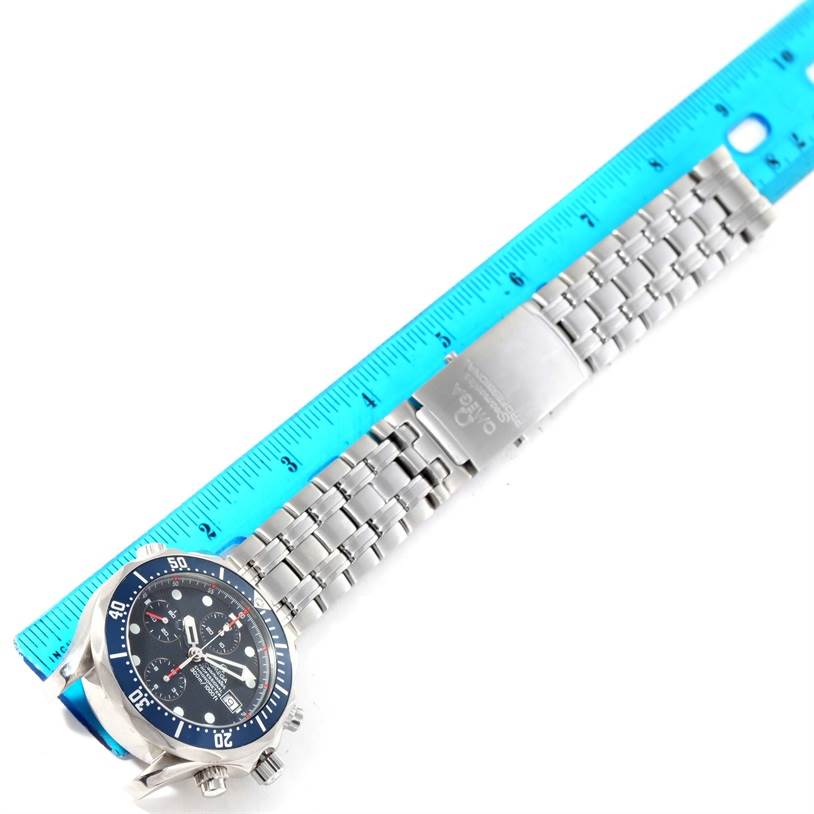 The Omega Seamaster 2599.80.00 Men
s Stainless Steel Blue Dial 2599.80.00 Men
s Stainless Steel Blue Dial watch is shown from a top-down angle, displaying its face, case, and bracelet with a blue ruler beside it for scale.