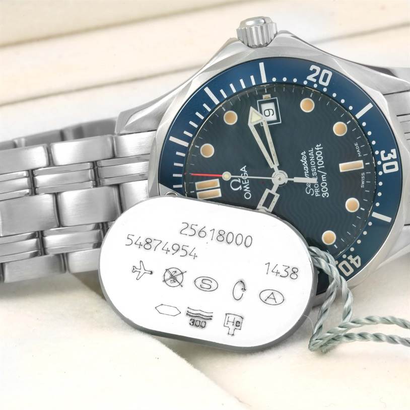 The image shows a side view of the Omega Seamaster 2561.80.00 Men
s Stainless Steel Blue Dial 2561.80.00 Men
s Stainless Steel Blue Dial watch with its metal bracelet and a tag displaying serial numbers and symbols.