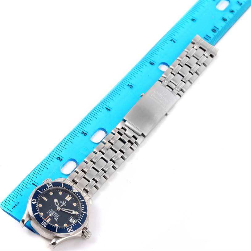 The image shows an Omega Seamaster 2551.80.00 Men
s Stainless Steel Blue Dial 2551.80.00 Men
s Stainless Steel Blue Dial watch laid flat beside a blue ruler, displaying its dial and stainless steel bracelet.