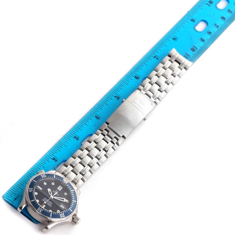 The Omega Seamaster 2561.80.00 Men
s Stainless Steel Blue Dial 2561.80.00 Men
s Stainless Steel Blue Dial watch is shown from a top-down angle with its stainless steel bracelet alongside a blue ruler.