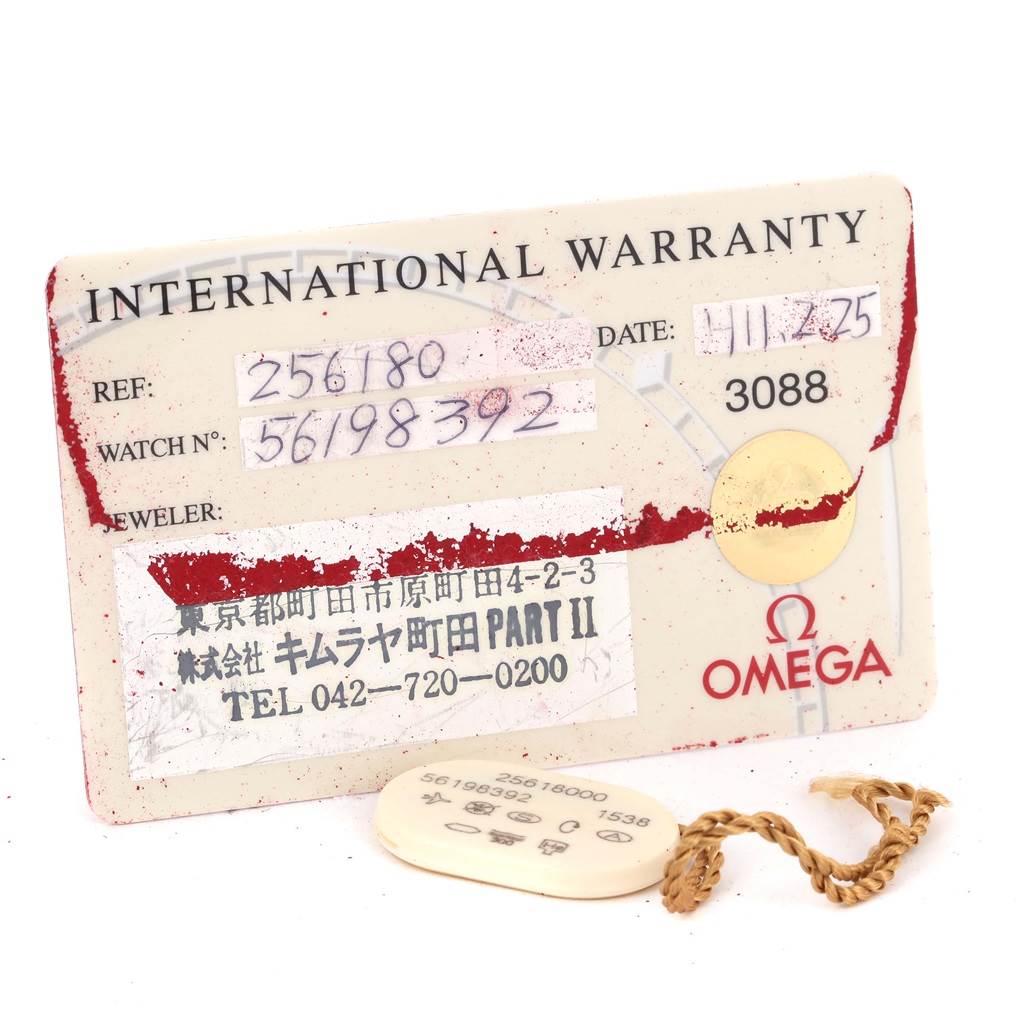 The image shows an angled view of an Omega Seamaster 2561.80.00 Men
s Stainless Steel Blue Dial 2561.80.00 Men
s Stainless Steel Blue Dial
s international warranty card and serial tag with a chain.