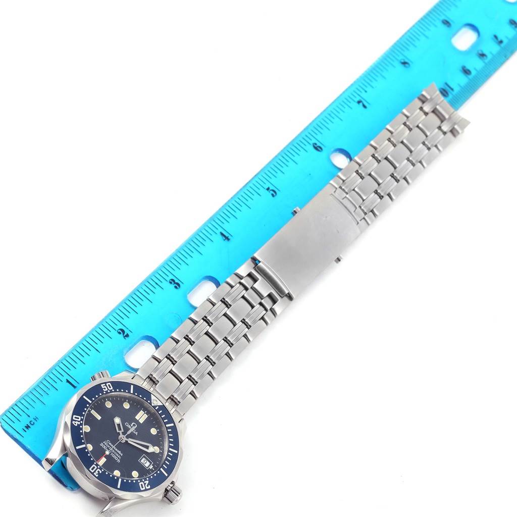 The Omega Seamaster 2561.80.00 Men
s Stainless Steel Blue Dial 2561.80.00 Men
s Stainless Steel Blue Dial watch is shown from the top, displaying its face, bezel, and metal bracelet against a blue ruler.