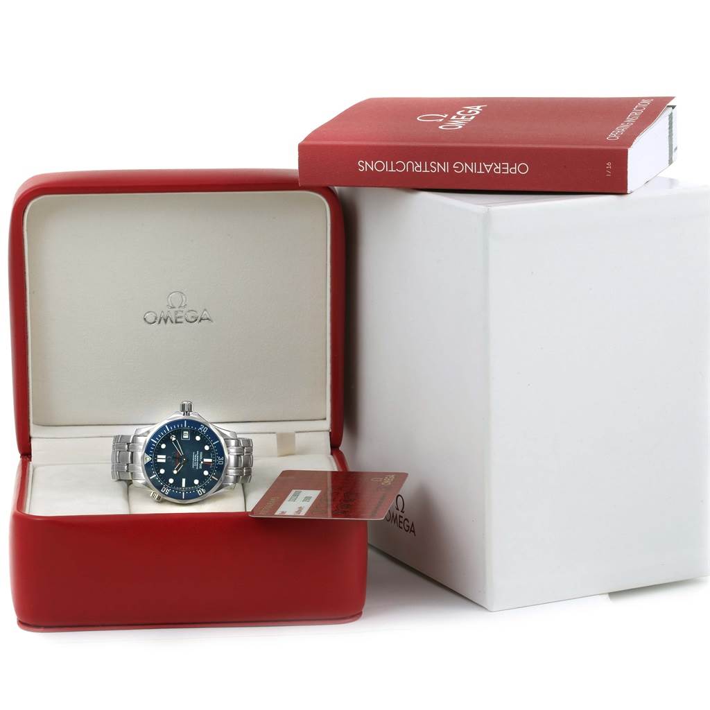 The image shows an Omega Seamaster 2222.80.00 Men
s Stainless Steel Blue Dial 2222.80.00 Men
s Stainless Steel Blue Dial watch from a front angle, displayed in its red case with an instruction manual on the side.