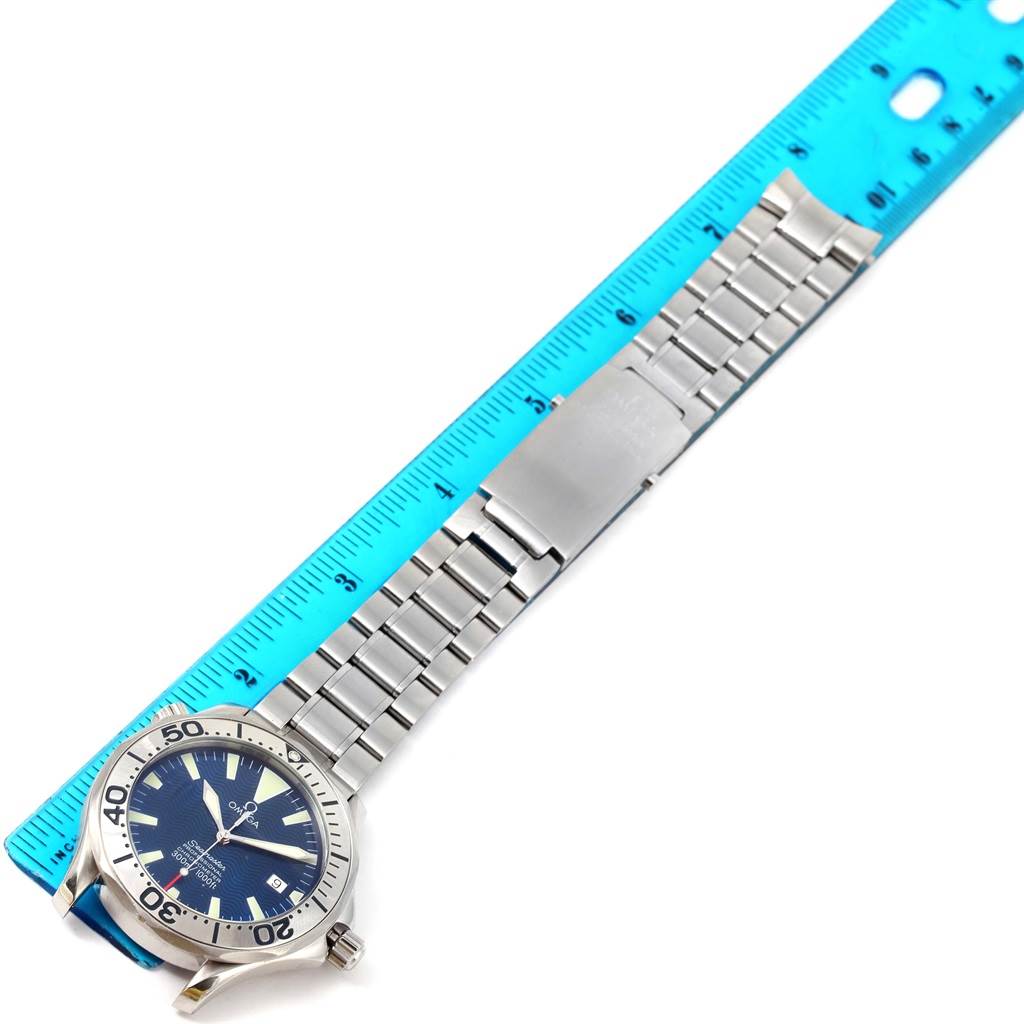 This image shows an Omega Seamaster 2255.80.00 Men
s Stainless Steel Blue Dial 2255.80.00 Men
s Stainless Steel Blue Dial watch laid flat next to a blue ruler, displaying its face, bezel, and metal bracelet.