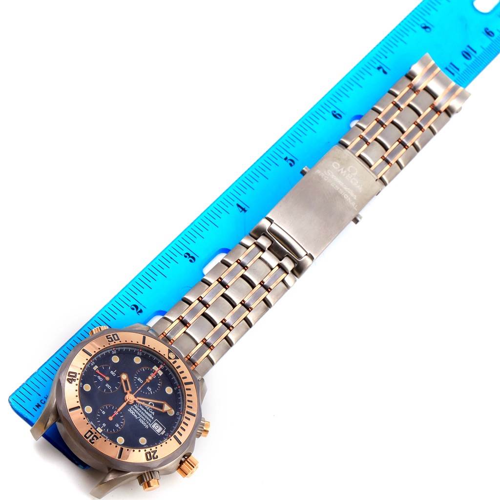 The image shows an Omega Seamaster 2296.80.00 Men's Titanium Blue Dial 2296.80.00 Men's Titanium Blue Dial watch with a metal bracelet, laid next to a blue ruler.