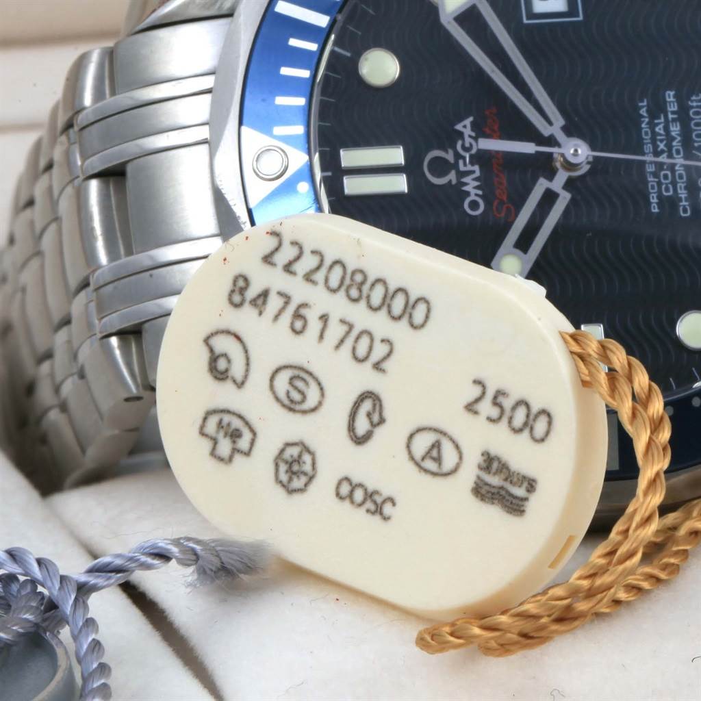 The Omega Seamaster 2220.80.00 Men
s Stainless Steel Blue Dial 2220.80.00 Men
s Stainless Steel Blue Dial watch is shown at an angle displaying part of the bracelet and a tag with model and certification details in the foreground.