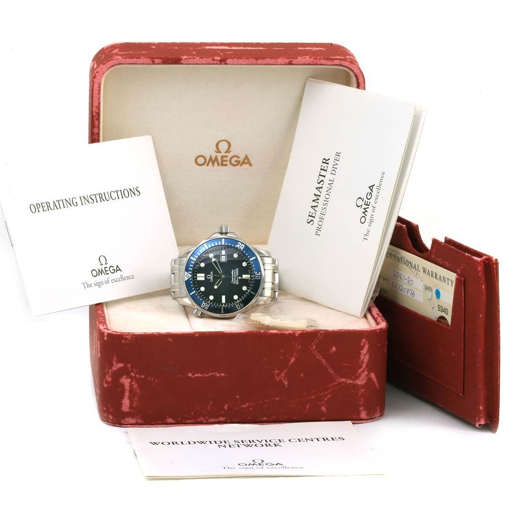 The Omega Seamaster 2541.80.00 Men
s Stainless Steel Blue Dial 2541.80.00 Men
s Stainless Steel Blue Dial watch is displayed front-facing in its box, surrounded by operating instructions, warranty card, and other documentation.