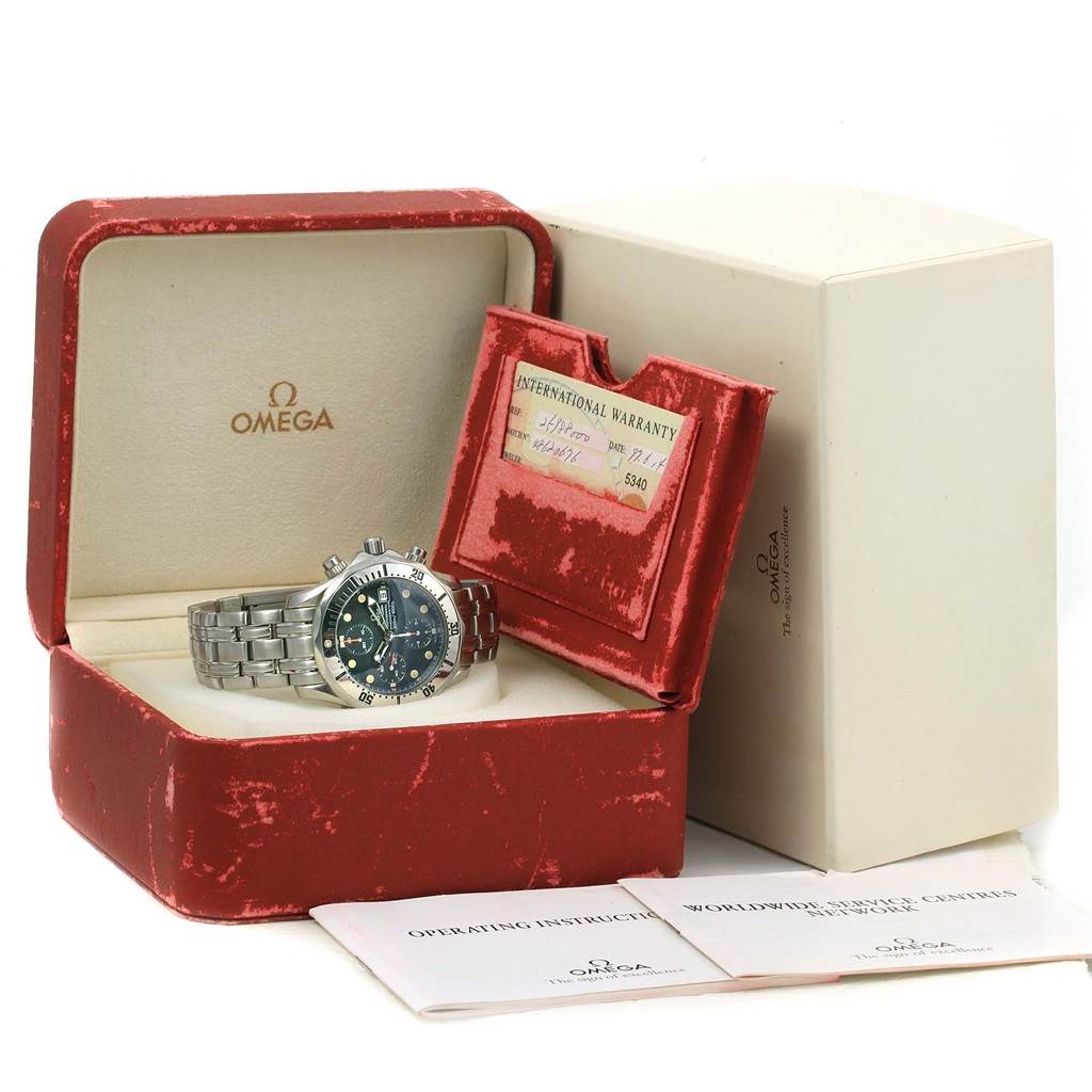 The image shows an Omega Seamaster 2598.80.00 Men
s Stainless Steel Blue Dial 2598.80.00 Men
s Stainless Steel Blue Dial watch in an opened red box, including warranty papers and an instruction manual.