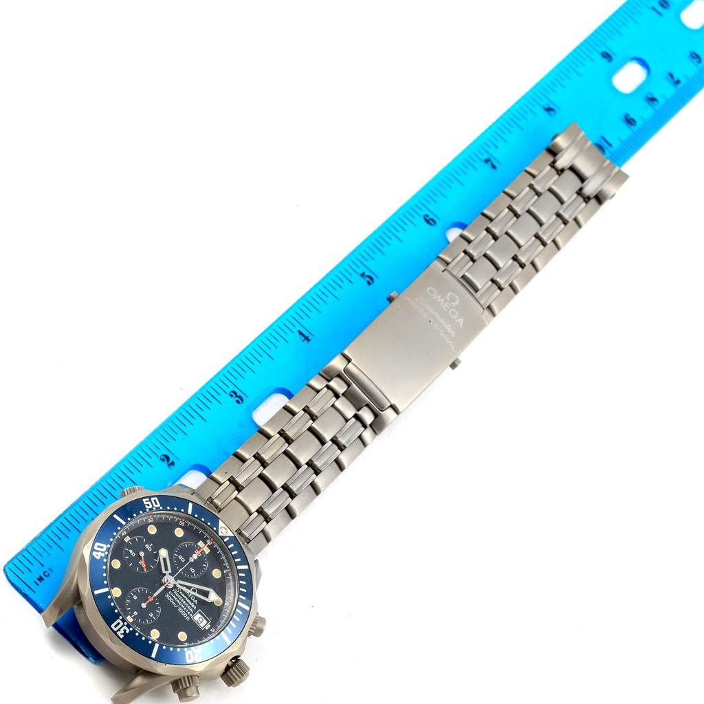 The Omega Seamaster 2298.80.00 Men
s Titanium Blue Dial 2298.80.00 Men
s Titanium Blue Dial watch is shown at a slight angle displaying its face, bezel, and stainless steel bracelet alongside a blue ruler for scale.