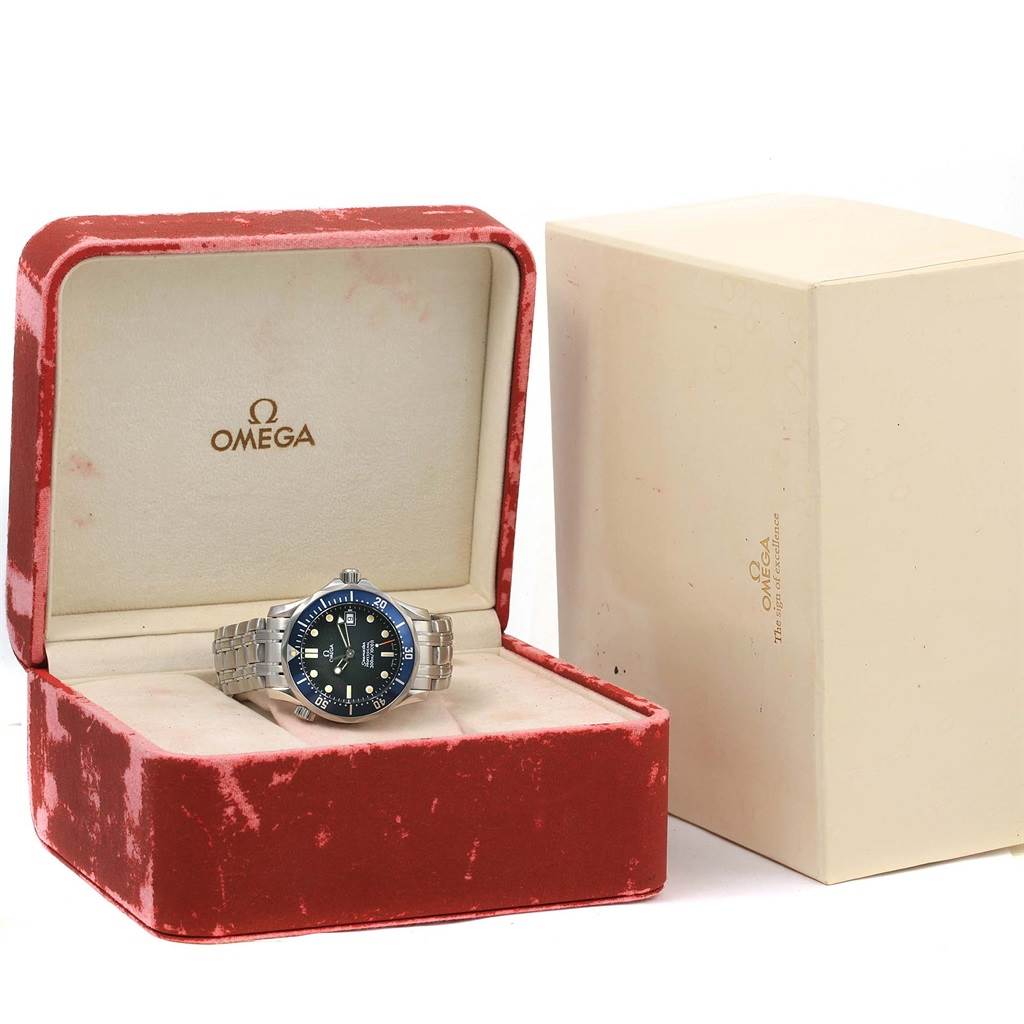 The image shows an Omega Seamaster 2561.80.00 Men
s Stainless Steel Blue Dial 2561.80.00 Men
s Stainless Steel Blue Dial watch and its accessories, including a red watch box and a beige outer box.