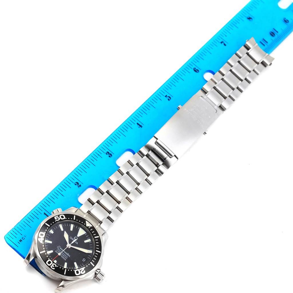 The image shows an Omega Seamaster 2252.50.00 Men
s Stainless Steel Black Dial 2252.50.00 Men
s Stainless Steel Black Dial watch laid flat next to a blue ruler, showcasing its stainless steel bracelet and clasp.