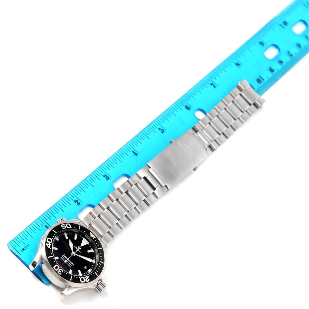 The image shows an Omega Seamaster 2262.50.00 Men
s Stainless Steel Black Dial 2262.50.00 Men
s Stainless Steel Black Dial watch laid flat next to a ruler, showcasing its dial, bezel, and metal bracelet.