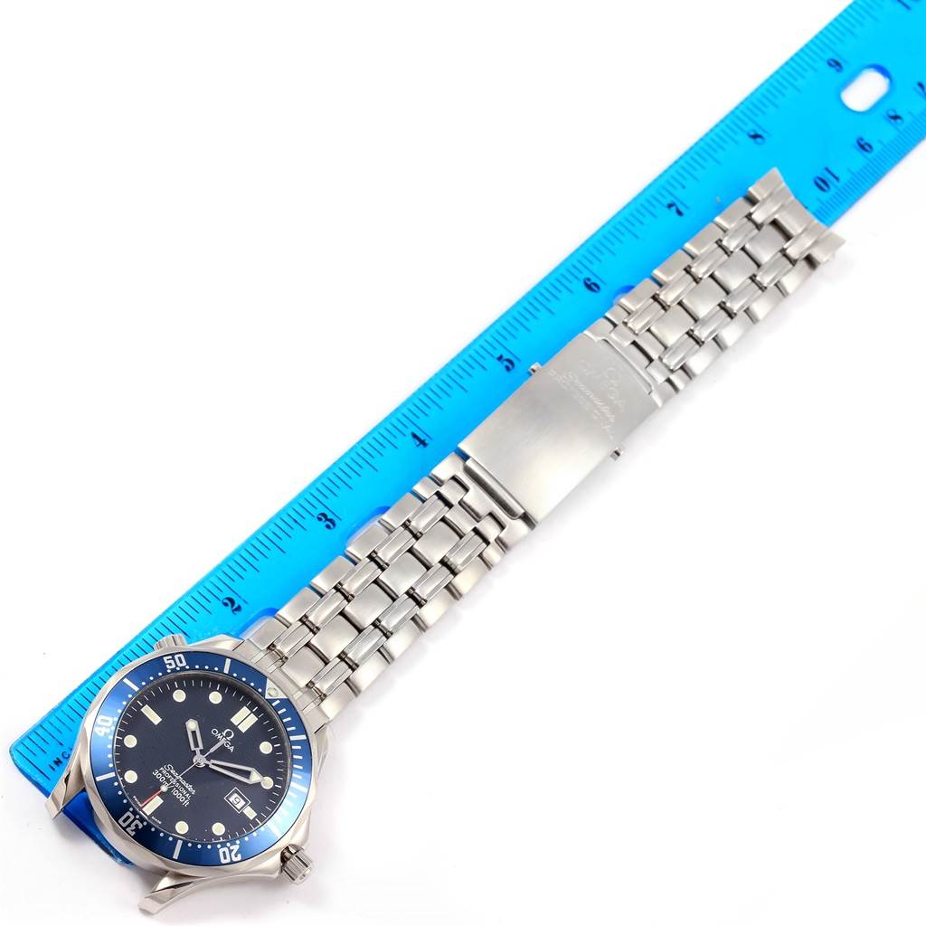 The image shows an Omega Seamaster 2541.80.00 Men
s Stainless Steel Blue Dial 2541.80.00 Men
s Stainless Steel Blue Dial watch laid flat with a blue ruler next to its stainless steel bracelet.