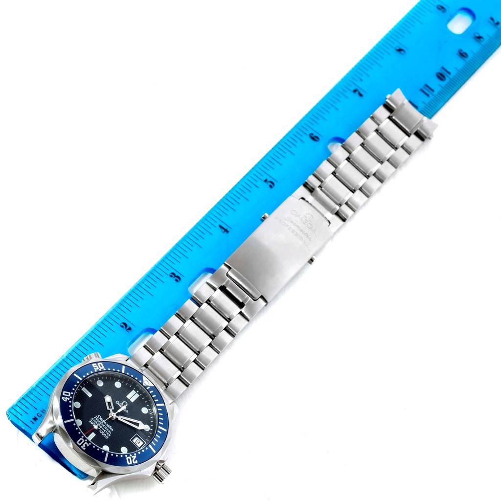 The Omega Seamaster 2551.80.00 Men
s Stainless Steel Blue Dial 2551.80.00 Men
s Stainless Steel Blue Dial watch is shown from an overhead angle, featuring its metal bracelet and dial, accompanied by a blue ruler for scale.