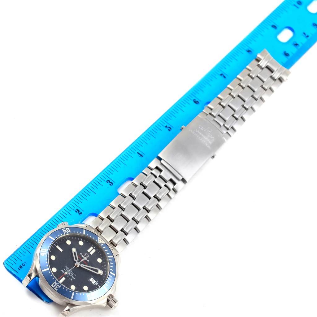 The Omega Seamaster 2220.80.00 Men
s Stainless Steel Blue Dial 2220.80.00 Men
s Stainless Steel Blue Dial watch is shown from an overhead angle, displaying its face, bezel, bracelet, and clasp alongside a blue ruler.