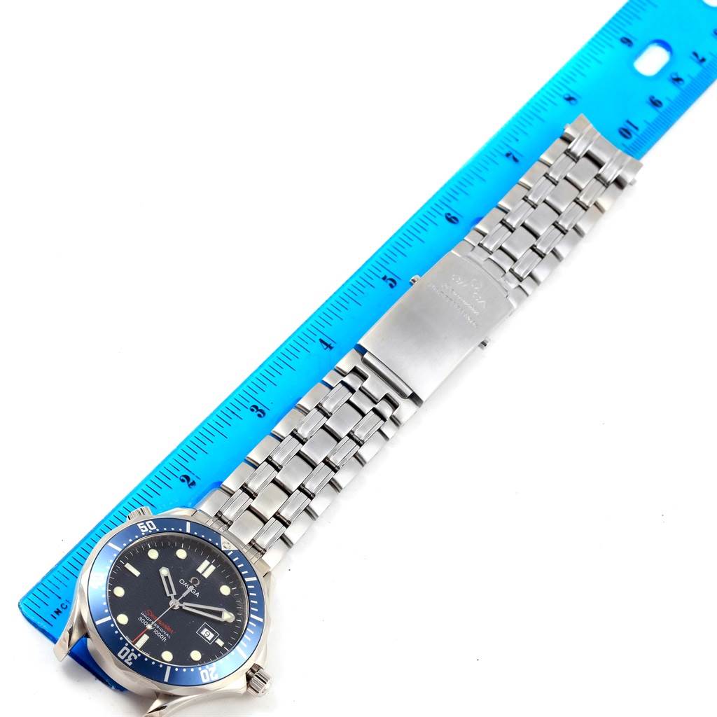 The image shows the face, bezel, and metal bracelet of an Omega Seamaster 2221.80.00 Men
s Stainless Steel Blue Dial 2221.80.00 Men
s Stainless Steel Blue Dial watch, lying flat next to a blue ruler for scale.