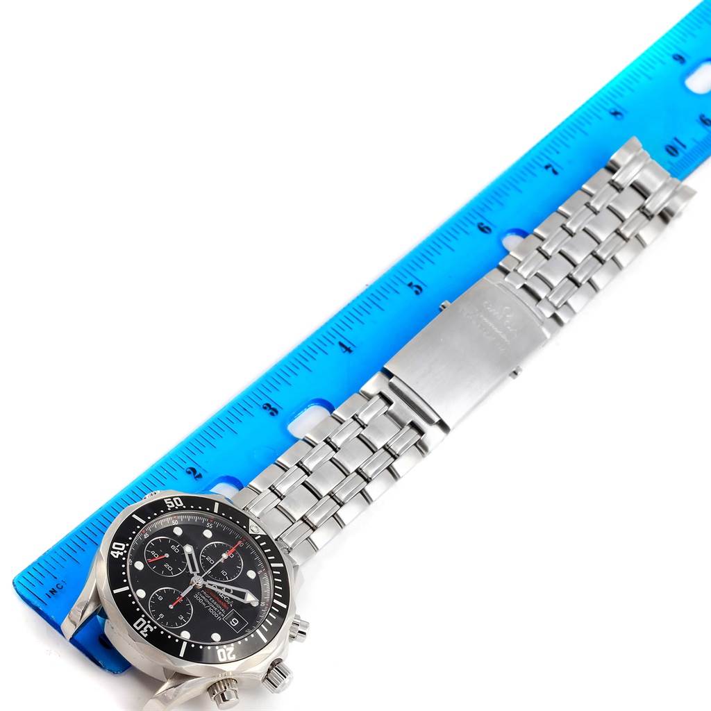 The Omega Seamaster 213.30.42.40.01.001 Men's Stainless Steel Black Dial 213.30.42.40.01.001 Men's Stainless Steel Black Dial watch is shown from a top-down angle, featuring the face, bezel, and metal bracelet next to a blue ruler.