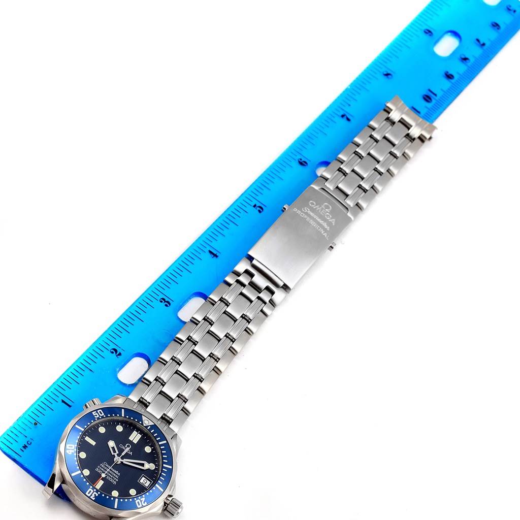 The image shows an Omega Seamaster 2551.80.00 Men
s Stainless Steel Blue Dial 2551.80.00 Men
s Stainless Steel Blue Dial watch laid flat, highlighting the face, bracelet, and clasp next to a blue ruler.