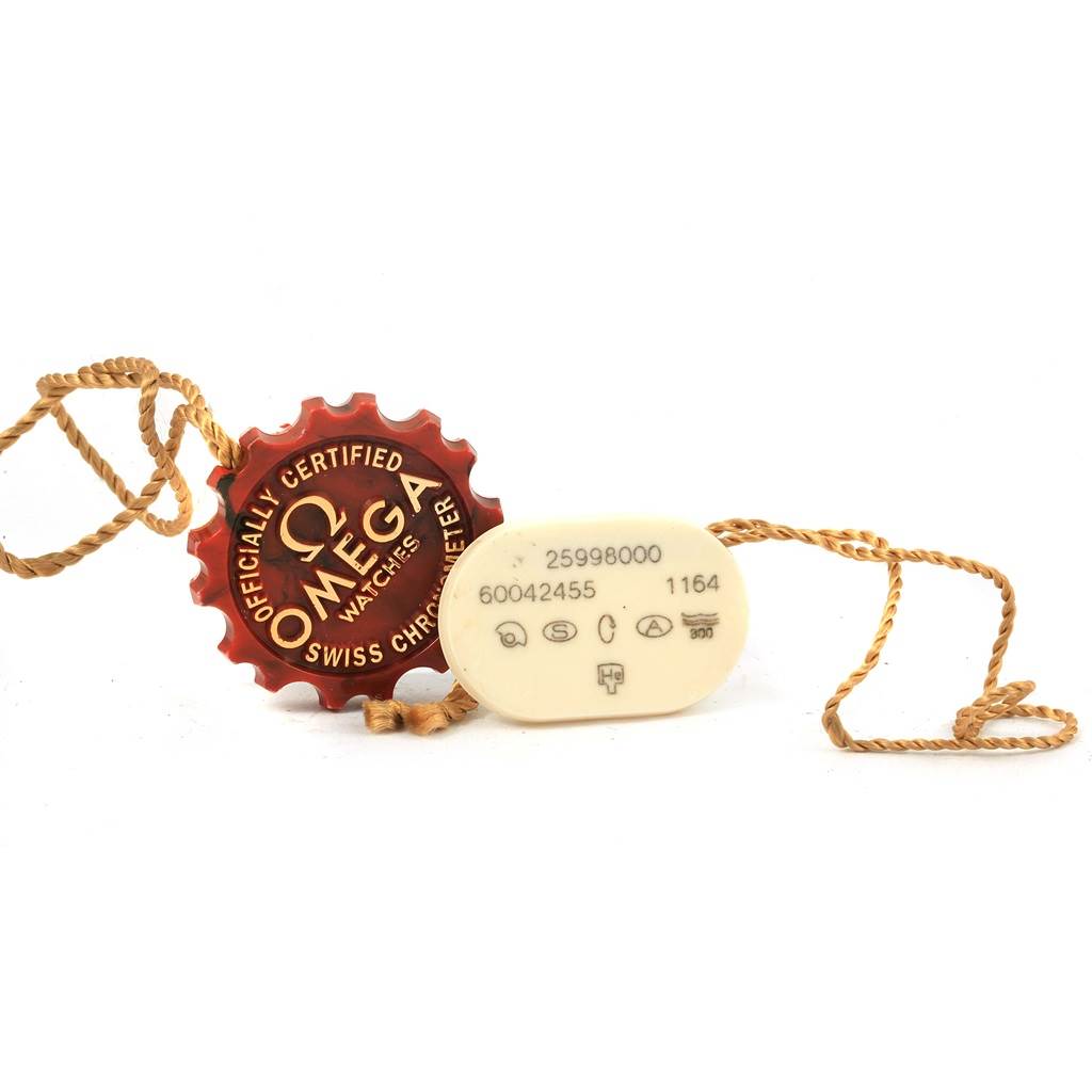 The image shows Omega Seamaster 2599.80.00 Men
s Stainless Steel Blue Dial 2599.80.00 Men
s Stainless Steel Blue Dial watch accessories: a red "officially certified" tag and a beige tag with serial and reference numbers.