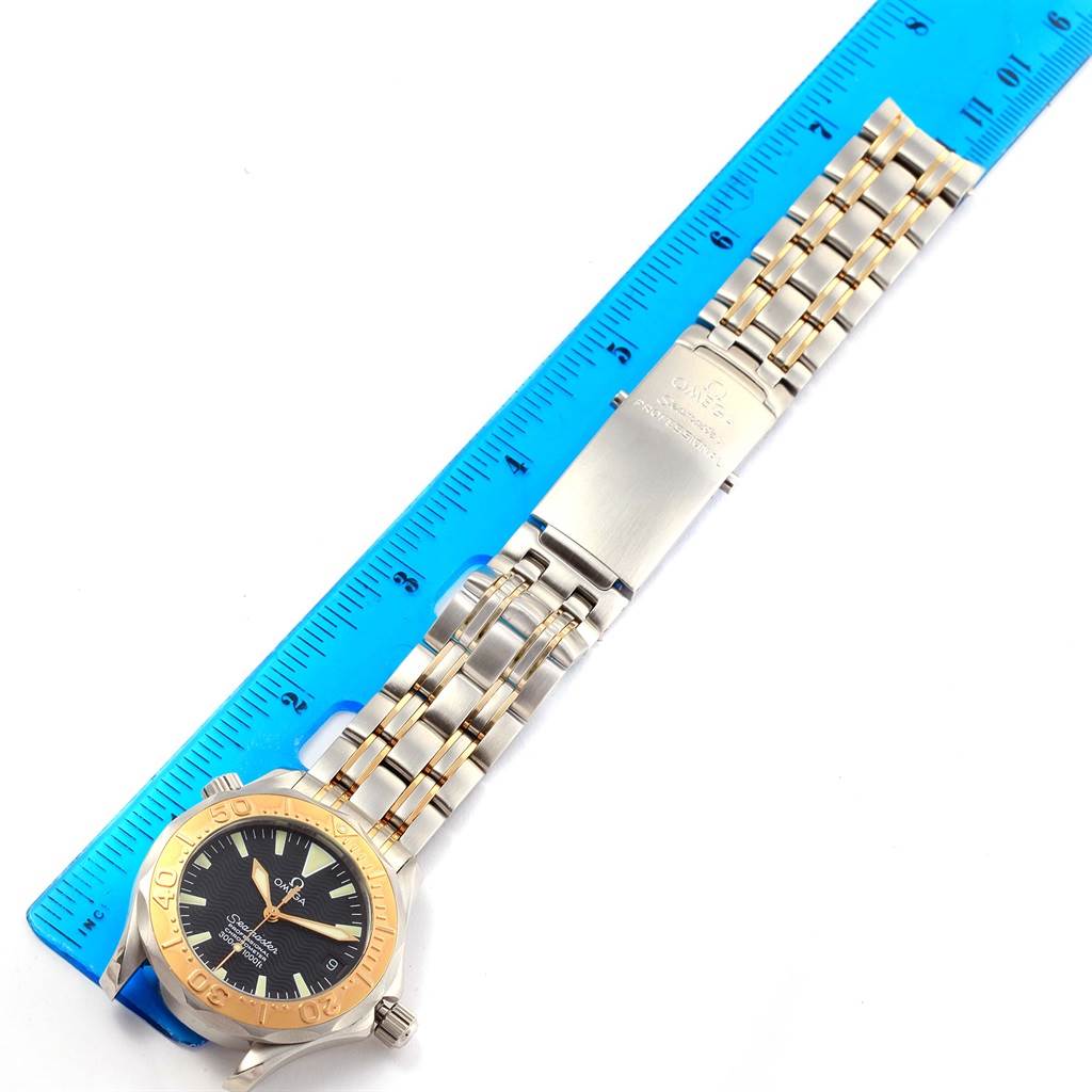 The Omega Seamaster Men
s Stainless Steel Black Dial Men
s Stainless Steel Black Dial watch is shown from above, featuring its gold bezel, black dial, and metal bracelet with a clasp.