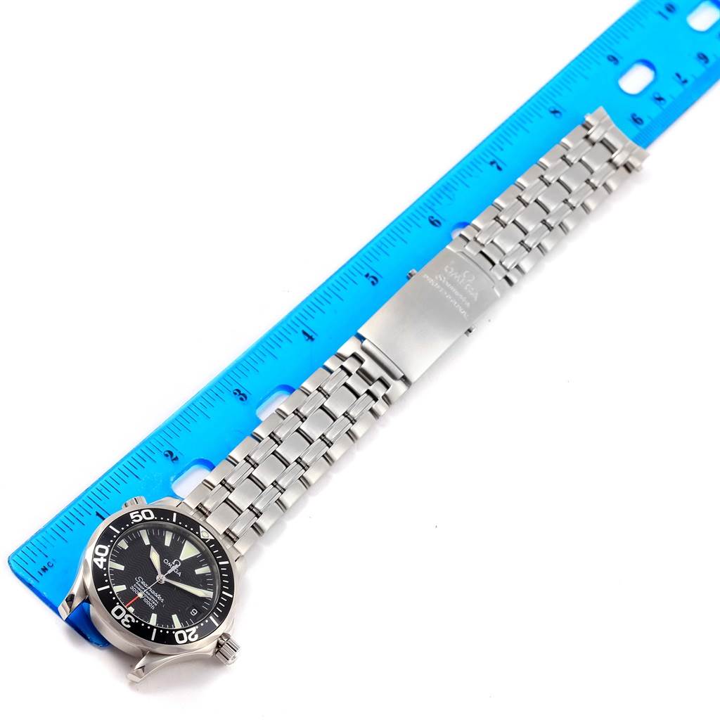 The Omega Seamaster 2252.50.00 Men's Stainless Steel Black Dial 2252.50.00 Men's Stainless Steel Black Dial watch is shown from a top-down angle, displaying its face, bezel, and metal bracelet next to a blue ruler.