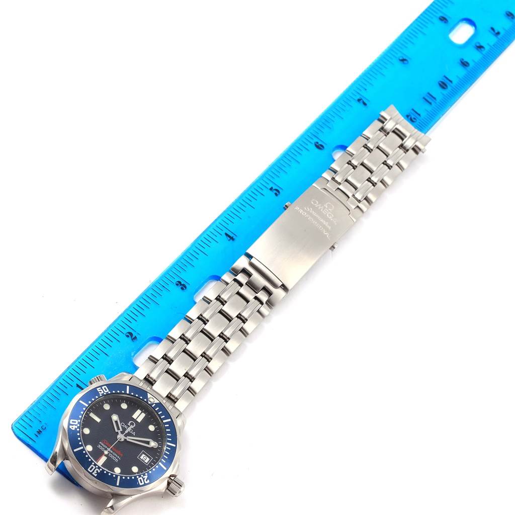 The image shows an Omega Seamaster 2223.80.00 Men
s Stainless Steel Blue Dial 2223.80.00 Men
s Stainless Steel Blue Dial watch laid flat next to a blue ruler, highlighting the stainless steel bracelet and clasp.