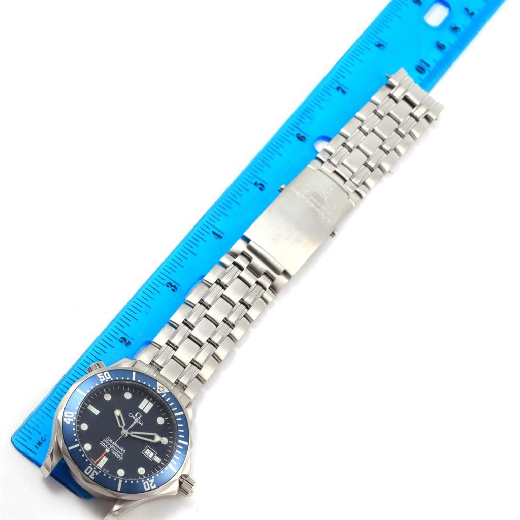 The image shows an Omega Seamaster 2541.80.00 Men
s Stainless Steel Blue Dial 2541.80.00 Men
s Stainless Steel Blue Dial watch laid flat beside a blue ruler, displaying its face, bezel, and metal bracelet.