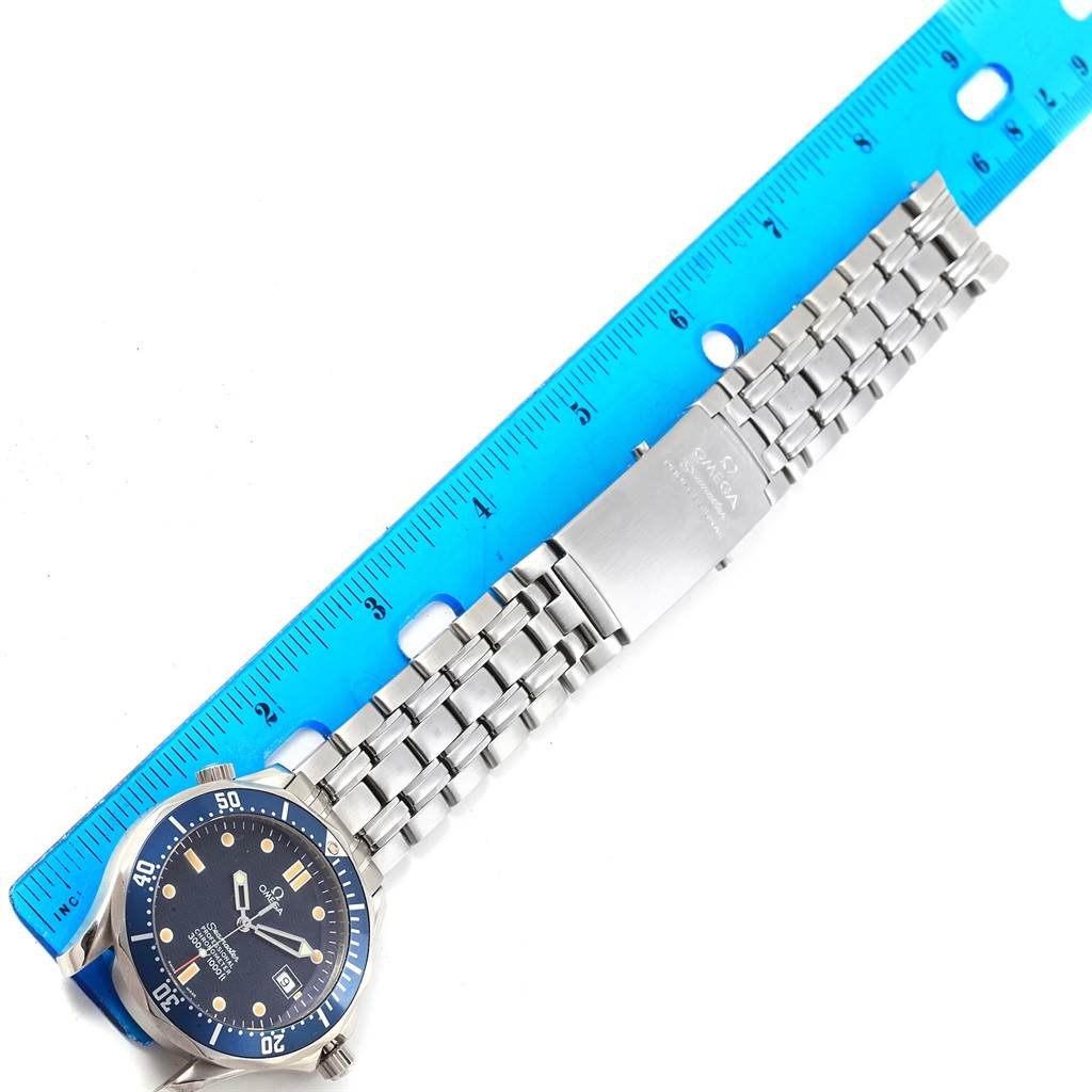 The image shows an overhead view of an Omega Seamaster 2531.80.00 Men
s Stainless Steel Blue Dial 2531.80.00 Men
s Stainless Steel Blue Dial watch with a stainless steel bracelet next to a blue ruler.