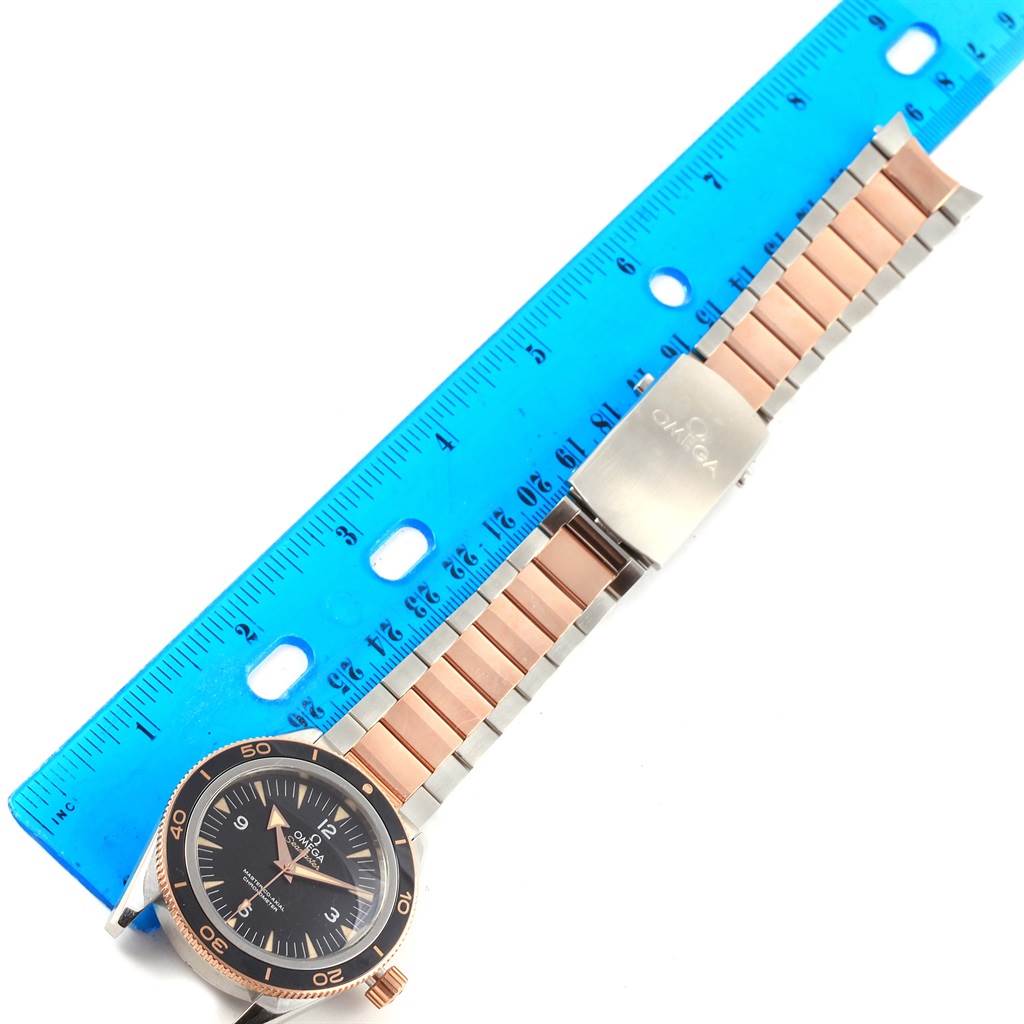 The image shows an Omega Seamaster 233.20.41.21.01.001 Men's Steel and Gold (two tone) Black Dial 233.20.41.21.01.001 Men's Steel and Gold (two tone) Black Dial watch laid flat, with its face, bezel, and two-tone strap visible next to a blue ruler.