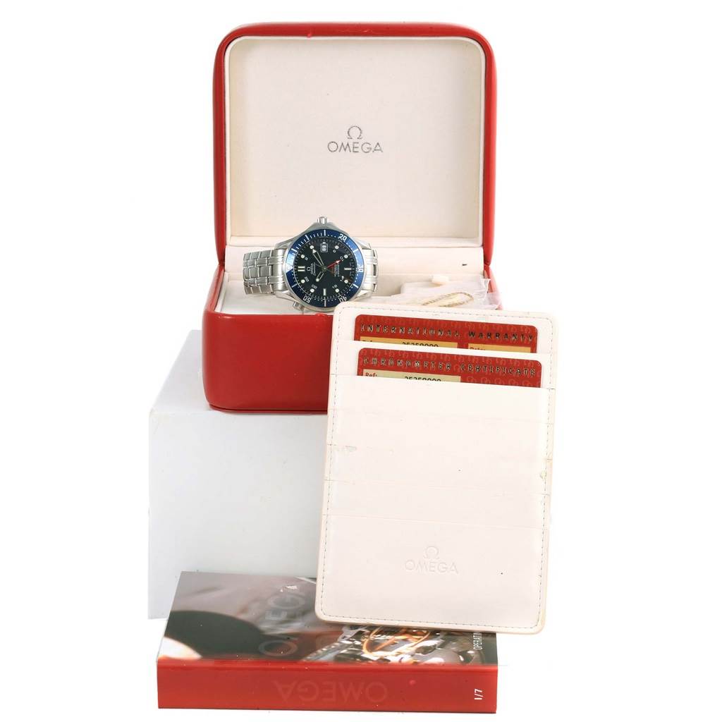 The image shows an Omega Seamaster 2535.80.00 Men
s Stainless Steel Blue Dial 2535.80.00 Men
s Stainless Steel Blue Dial watch in its open box, accompanied by warranty cards in a holder, all displayed on a stand.