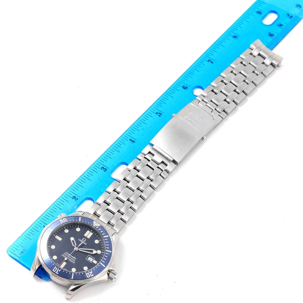 The Omega Seamaster 2541.80.00 Men
s Stainless Steel Blue Dial 2541.80.00 Men
s Stainless Steel Blue Dial watch is shown from a top-down angle, displaying the face, bezel, and metal bracelet next to a blue ruler.