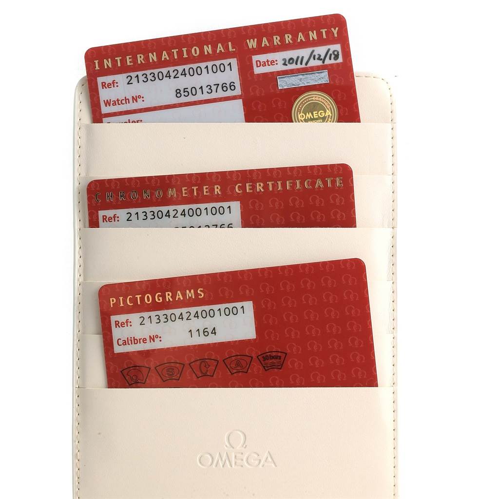 The image shows warranty and certification cards in a cream-colored Omega cardholder for the Seamaster model.