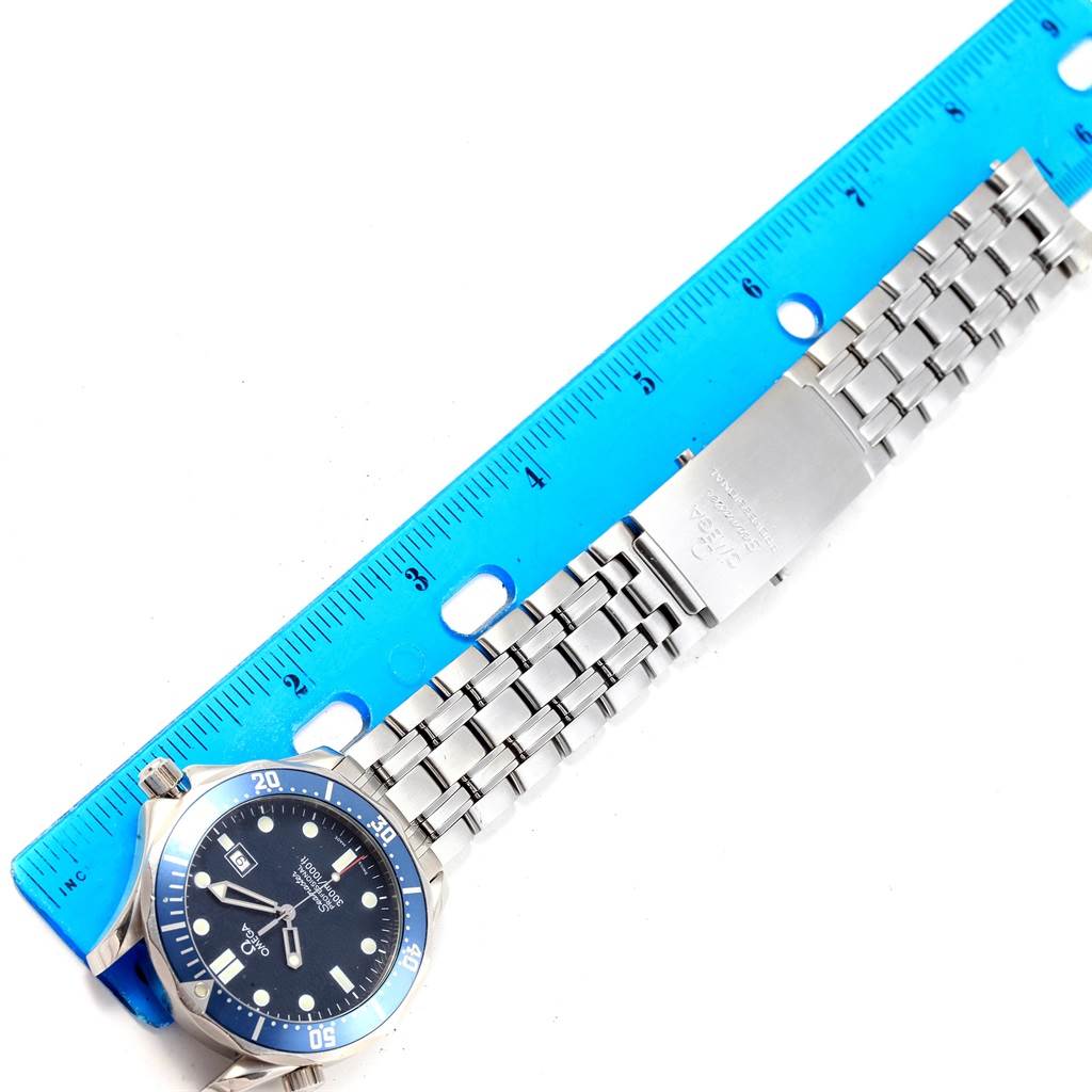 The Omega Seamaster 2541.80.00 Men
s Stainless Steel Blue Dial 2541.80.00 Men
s Stainless Steel Blue Dial watch is shown from a top-down angle, displaying the face, dial, and metal bracelet alongside a blue ruler.